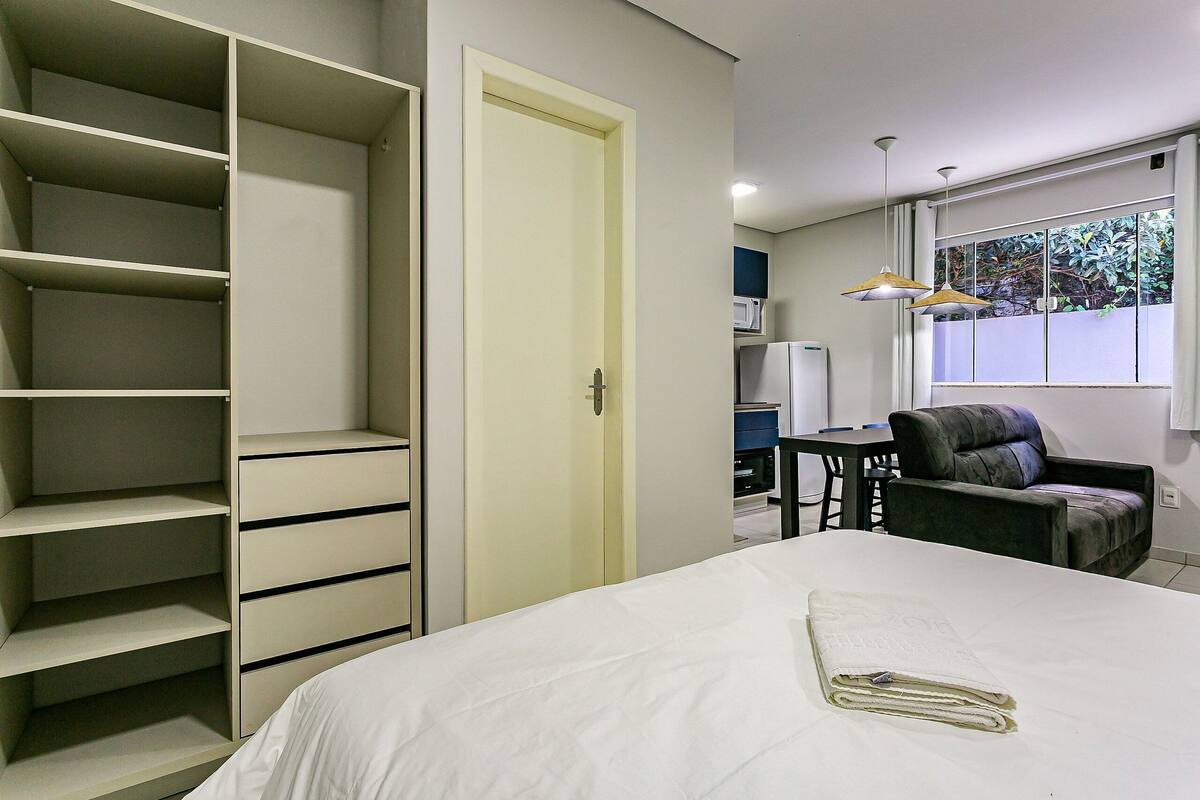 Un dormitorio con cama, armario, escritorio, silla y ventana con vistas.