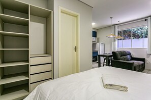 Un dormitorio con cama, armario, escritorio, silla y ventana con vistas.