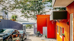Un bâtiment à la façade rouge, avec une moto garée devant et une voiture garée sur le côté gauche.