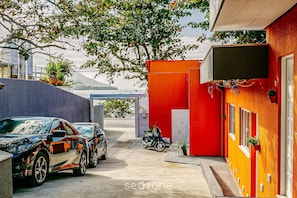 A building with a red exterior, a motorcycle parked in front, and a car parked to the left. - SDR Aptos de frente para Lagoa Conceição (Florianópolis)