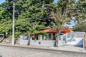 A residential building with a red roof, white walls, and a gated entrance. - SDR Aptos de frente para Lagoa Conceição (Florianópolis)