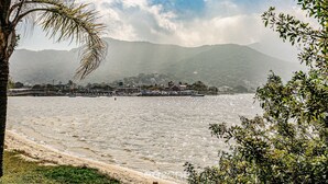 Une vue côtière avec une plage, des palmiers et des montagnes en arrière-plan.