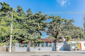 A building with a red-tiled roof, surrounded by trees and power lines. - SDR Aptos de frente para Lagoa Conceição (Florianópolis)