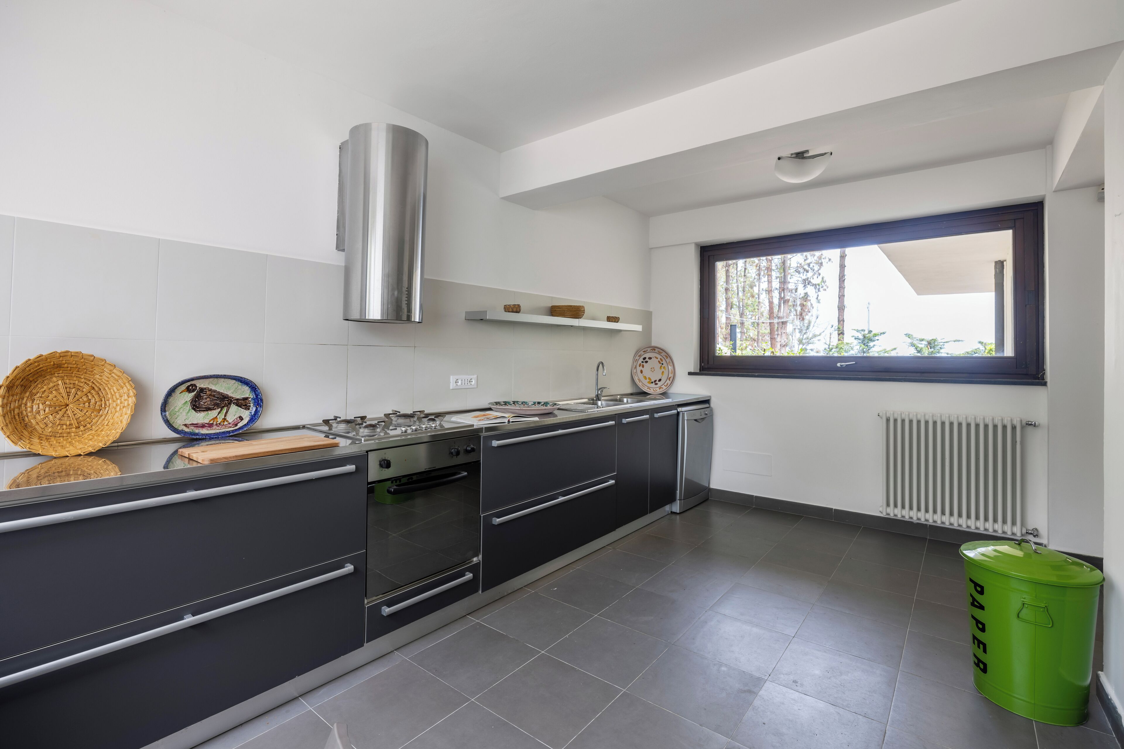 A modern kitchen with a stove, oven, and a window with a view of trees.