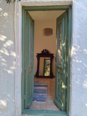A hallway with a wooden door frame, a hanging light fixture, and a patterned rug.