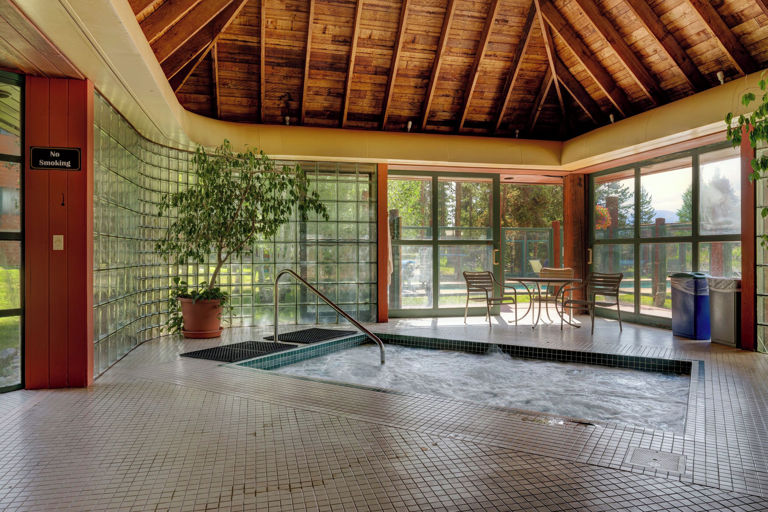 A spa area with a hot tub, a potted plant, and a 'No Smoking' sign.