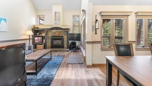 A spacious living room with a fireplace, a ceiling fan, and large windows offering a view of the outdoors. - Ss1902-1 (Keystone)