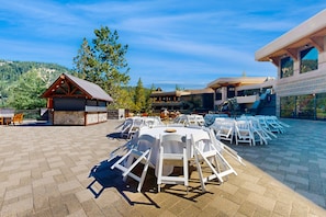 Enjoy al fresco dining with a view of the surrounding landscape from this outdoor dining area, featuring round tables and chairs in a semi-circular arrangement.