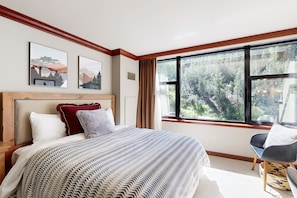 Relax in this serene retreat with a large bed, framed views of the forest, and a cozy reading nook.