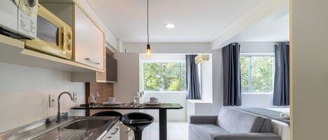 A compact kitchen with a sink, stove, and a dining area with a table and chairs.