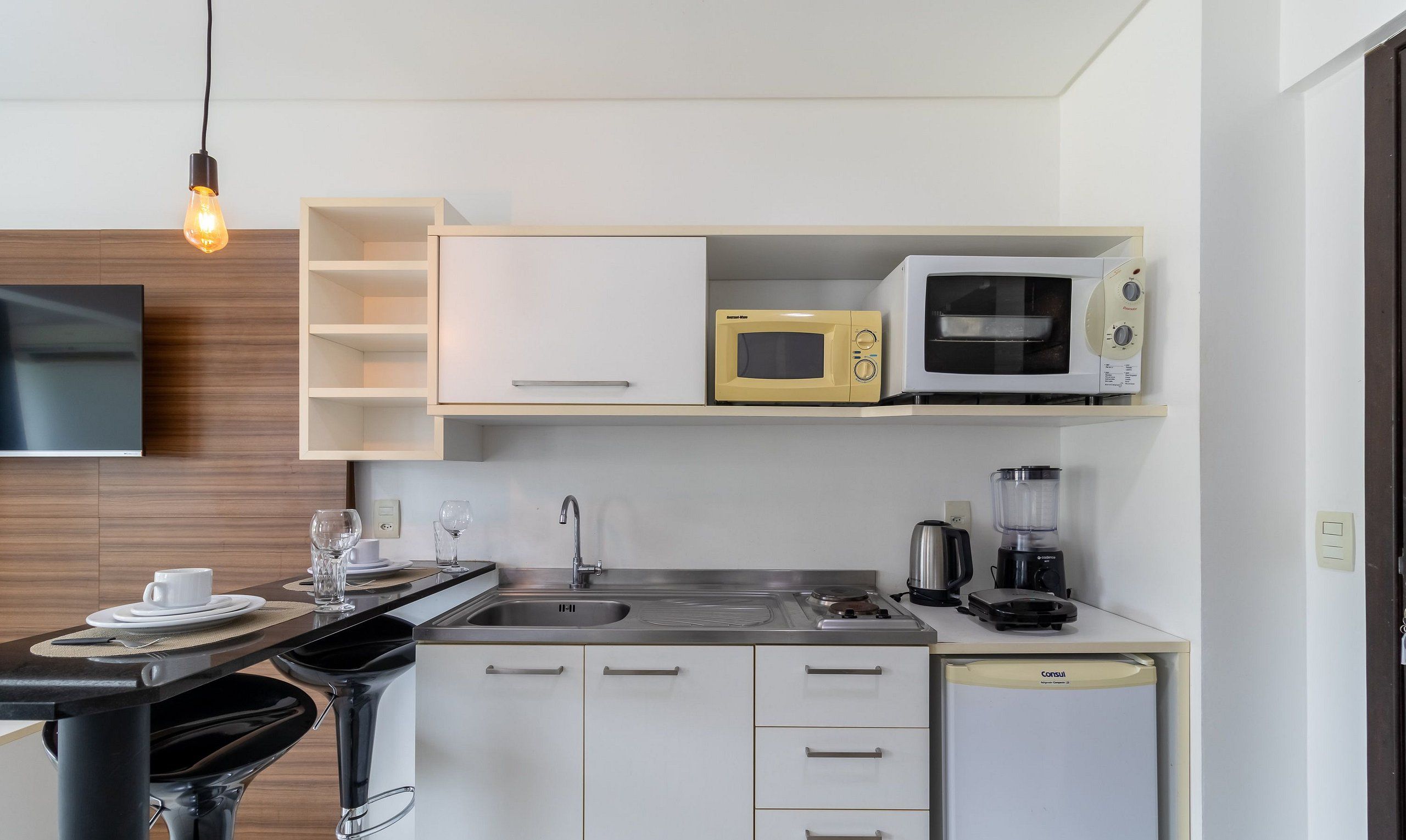 Eine moderne Küche mit Flachbildfernseher, Mikrowelle, Kaffeemaschine und Mixer.