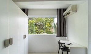 A minimalist room with a large window, a desk, and a chair. - SPTs Studios Convenientes em Blumenau (Blumenau)