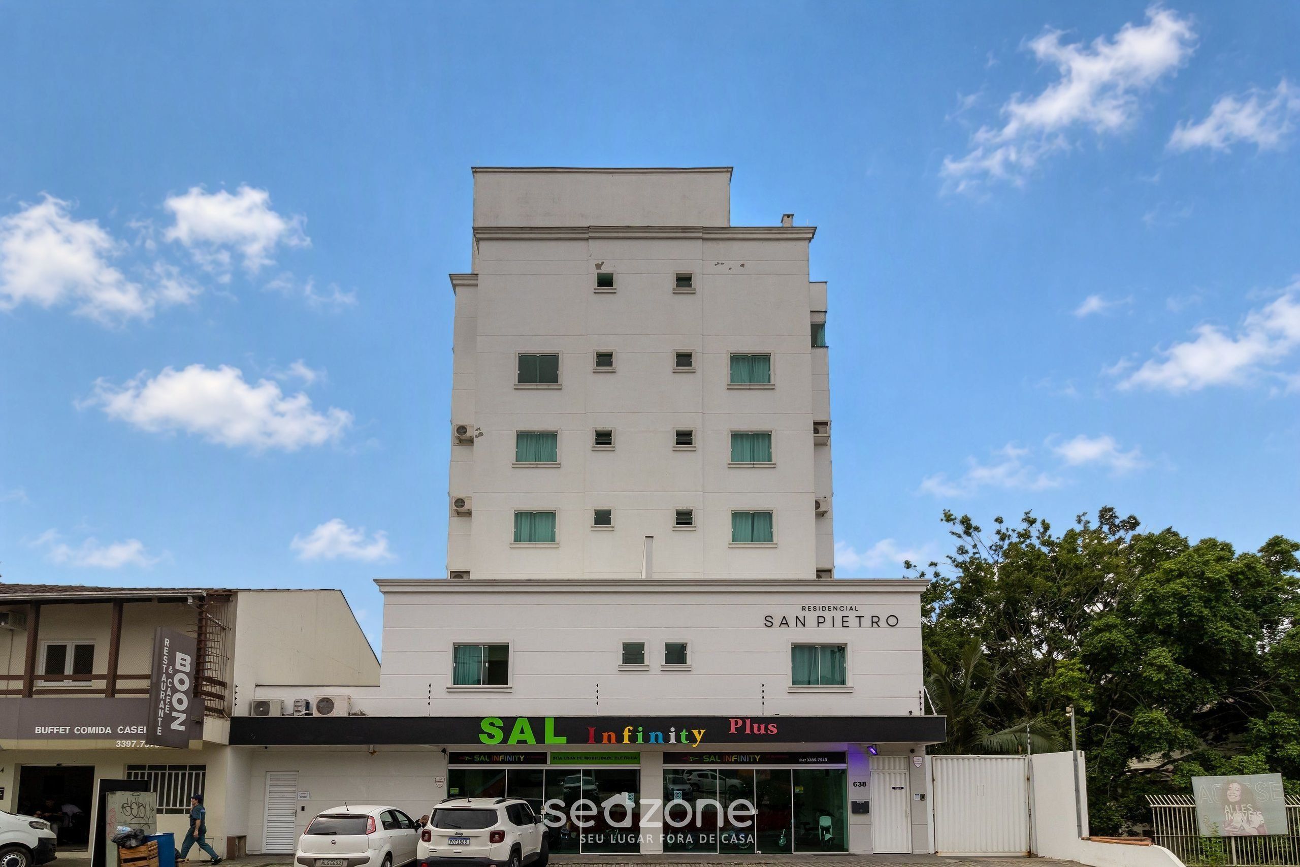 Un edificio de varios pisos con un cartel que dice 'SAL Infinity Plus' al nivel de la calle.
