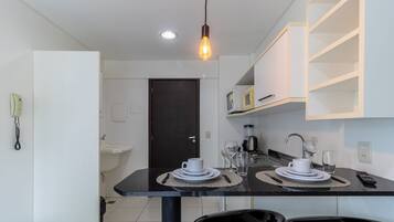 A modern kitchen with a dining table set for two, a coffee maker, and a microwave on the counter.