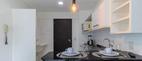 Una cocina moderna con una mesa de comedor preparada para dos personas, una cafetera y un microondas en la encimera.