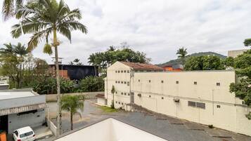 A residential area with a white building, a parked white car, and palm trees.