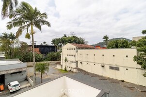 A residential area with a white building, a parked white car, and palm trees.
