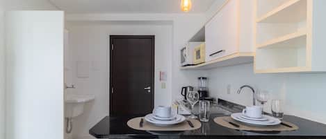 A modern kitchen with a black countertop, white cabinets, a microwave, a coffee maker, and a sink.