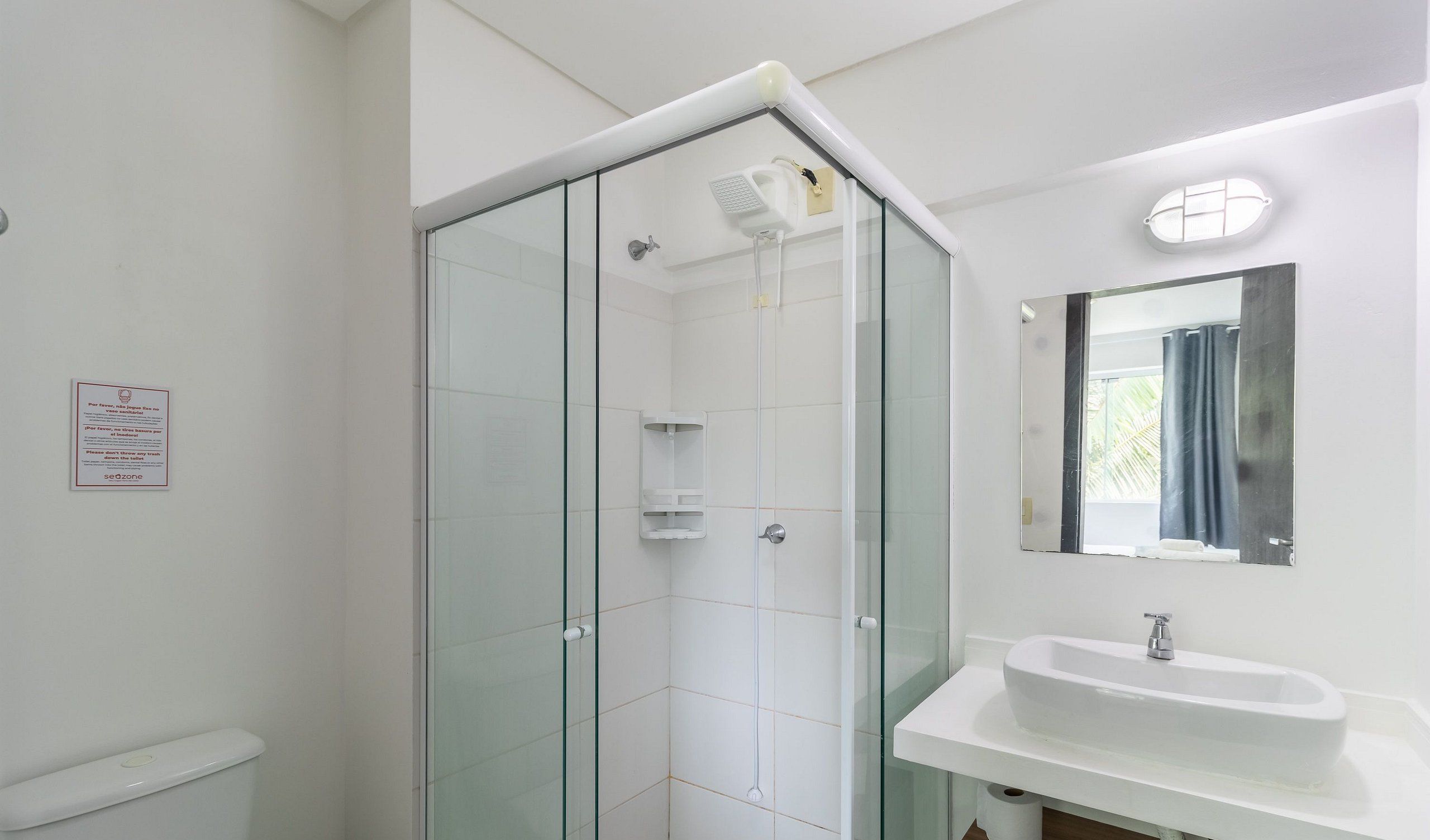 A modern bathroom with a glass-enclosed shower, a white sink, and a mirror above it.
