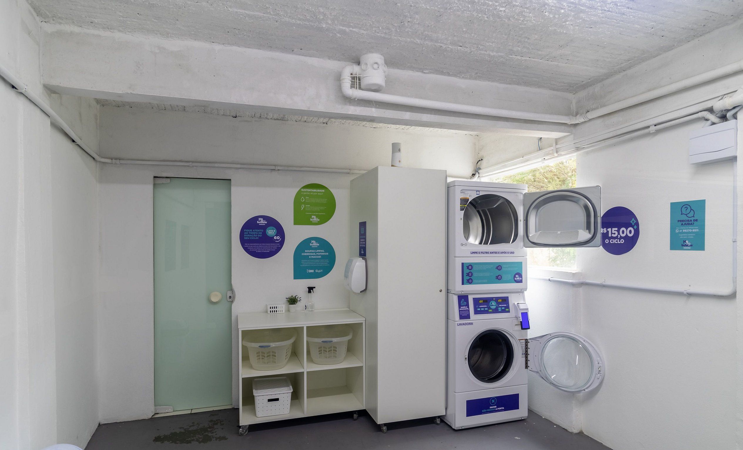 A laundry facility with a washing machine, a drying machine, and a sink. There are informational signs on the wall.