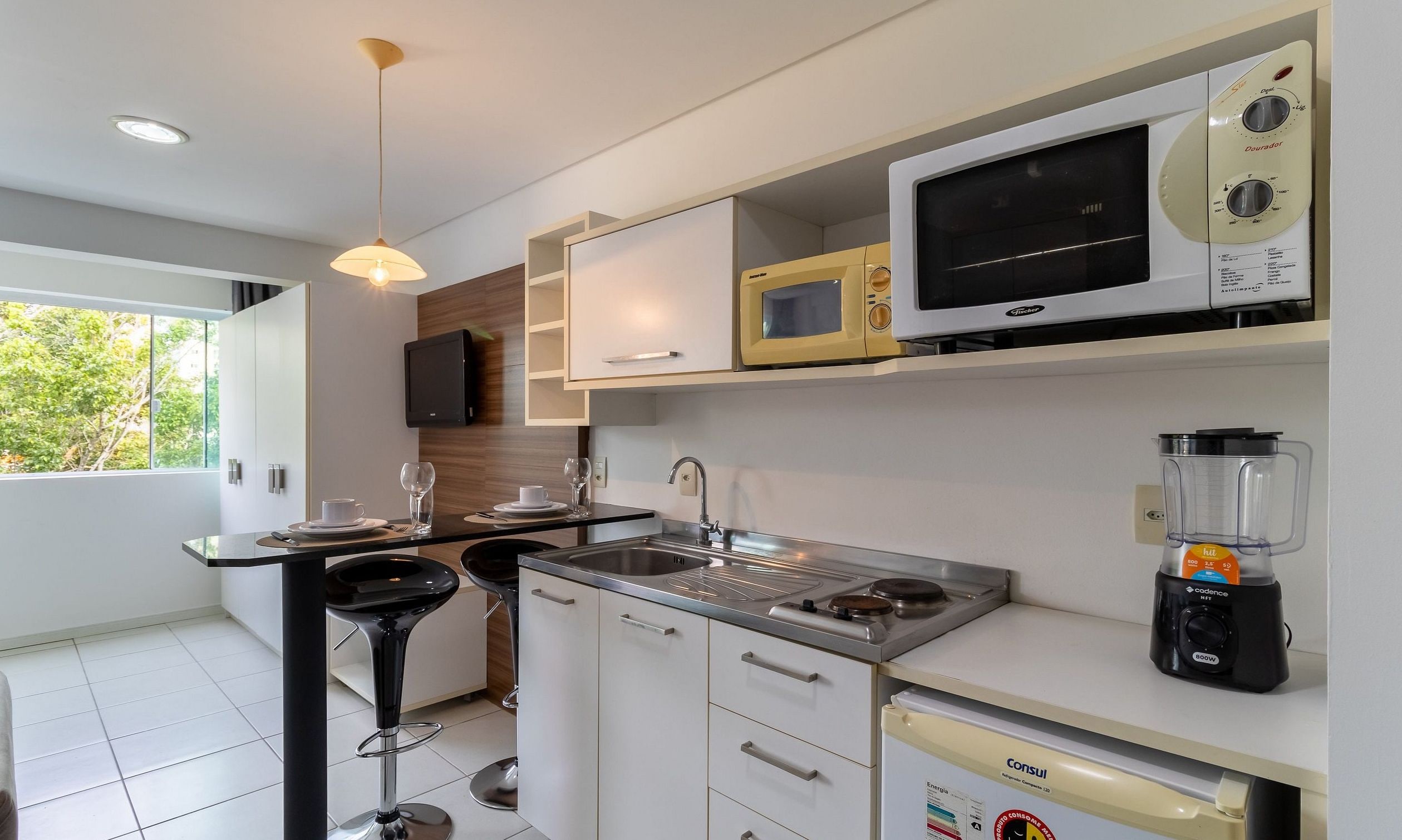 A modern kitchen with a built-in microwave, a coffee machine, and a blender on the counter.