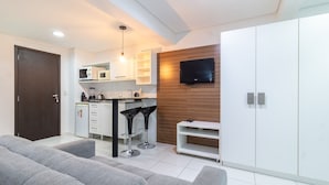 A modern kitchen with white cabinets, a black countertop, and a built-in microwave. - SPTs Studios Convenientes em Blumenau (Blumenau)