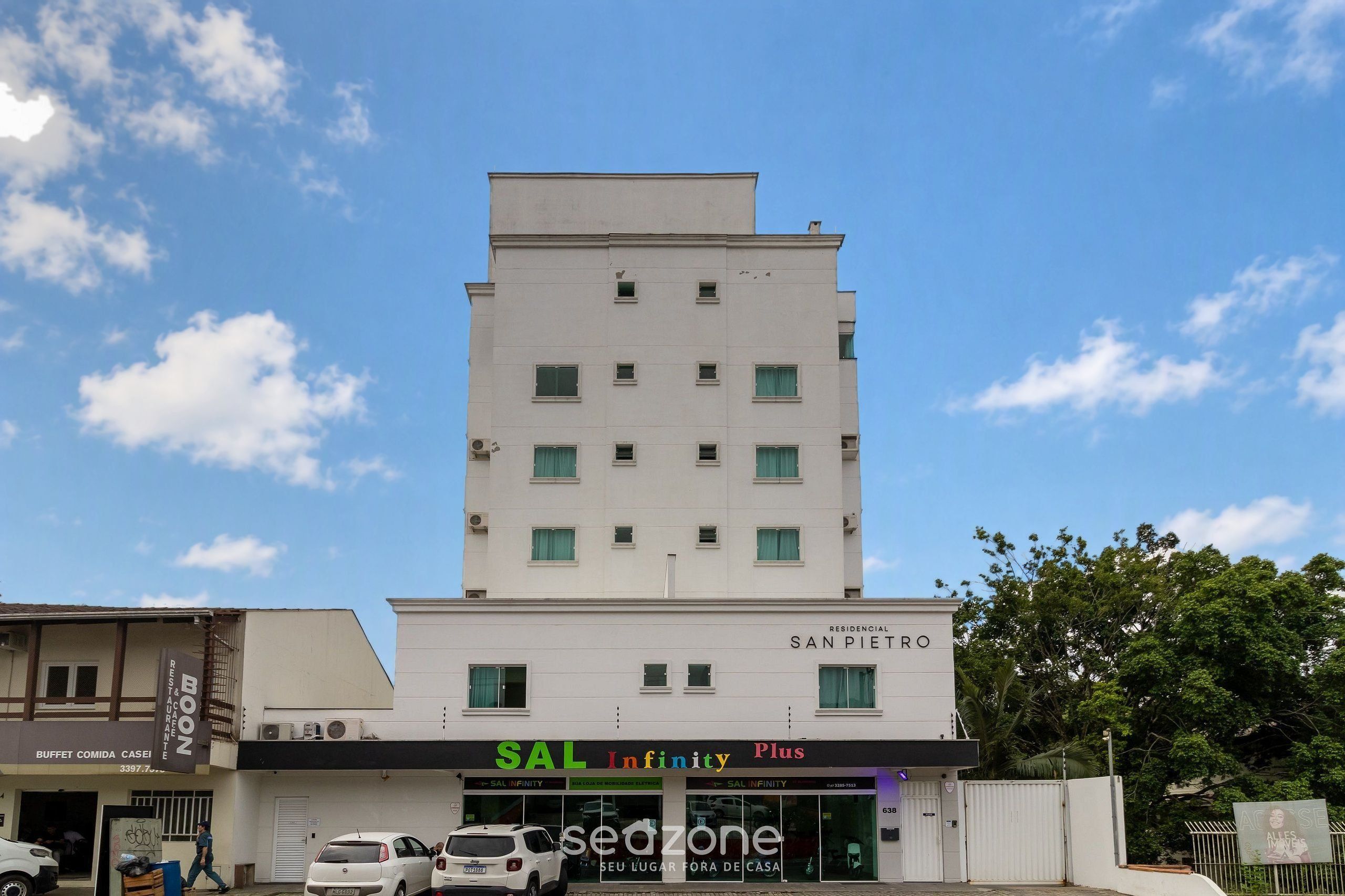 A multi-story building with a commercial ground floor featuring a restaurant and a car dealership.