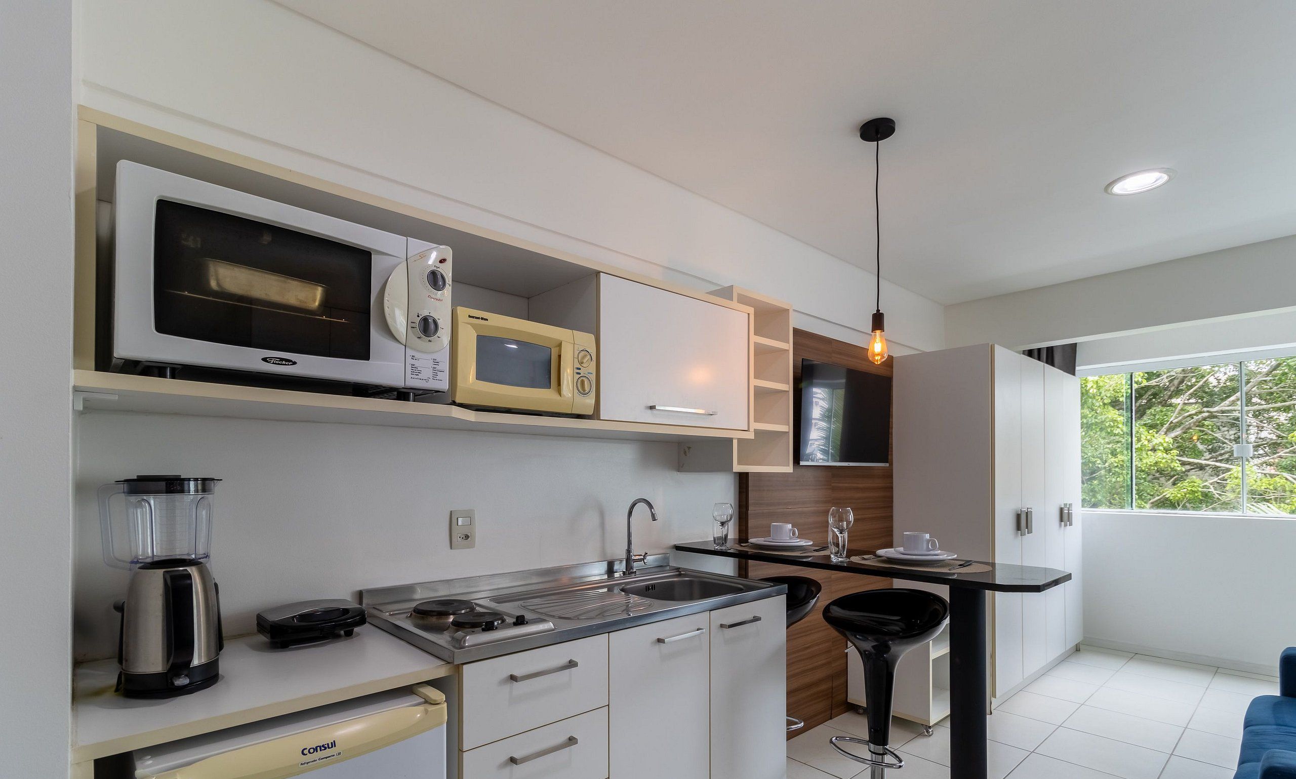 A modern kitchen with a built-in microwave, a coffee maker, and a sink.