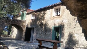 A rustic stone building with a wooden bench and a clear chair in front.