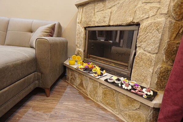 A living room with a stone fireplace, a sofa, and a tray of snacks and drinks. -  Ayder Palazzo (Çamlihemsin)