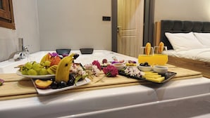 Ein Frühstücksangebot mit Obst, Käse und Getränken auf einem Tablett in einem Hotelzimmer.