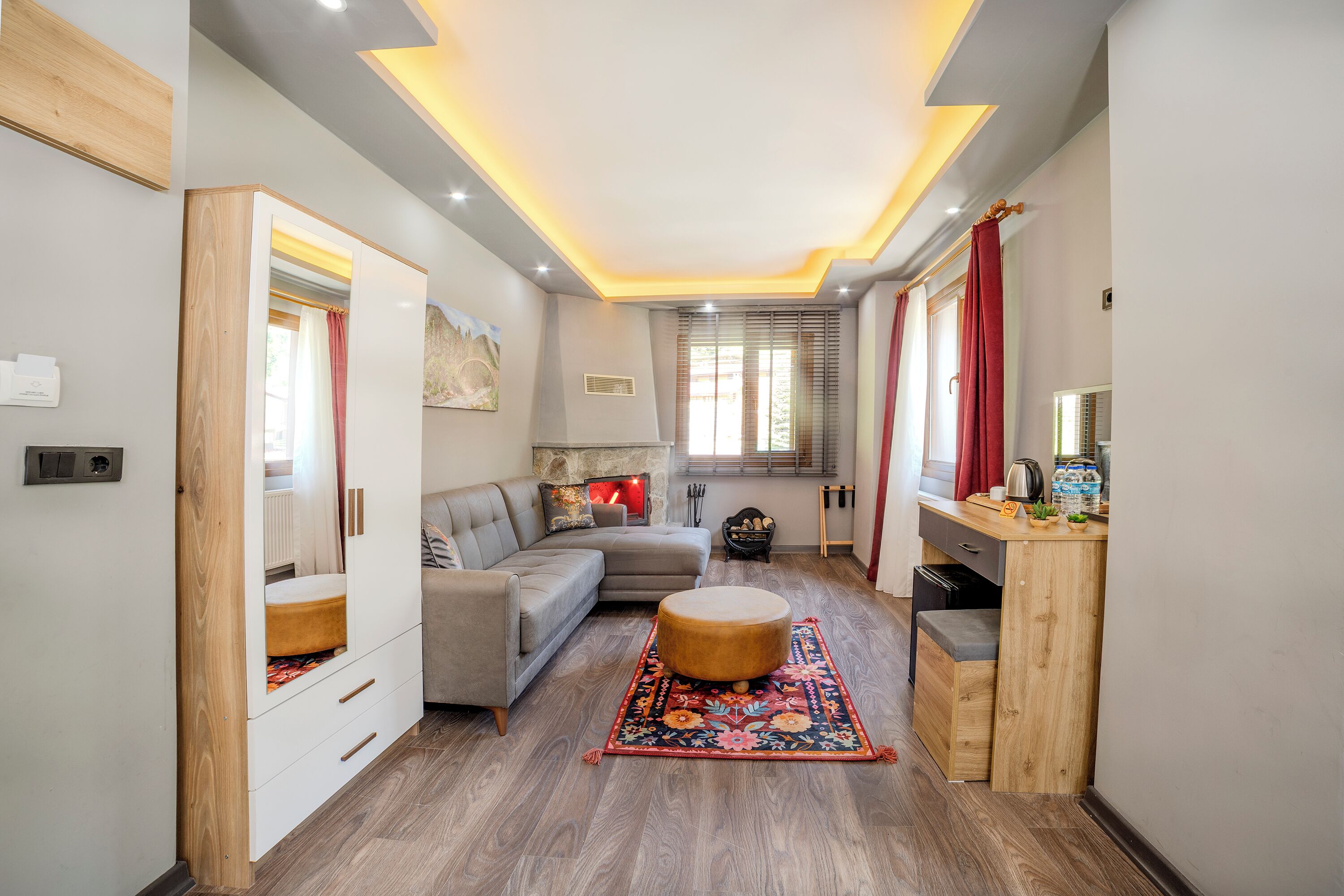 A modern living room with a sofa, ottoman, and wooden cabinet.