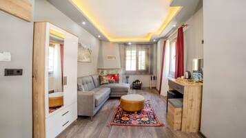 A modern living room with a sofa, ottoman, and wooden cabinet.
