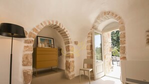 A room with exposed brick walls, a wooden cabinet, a chair, and a lamp.
