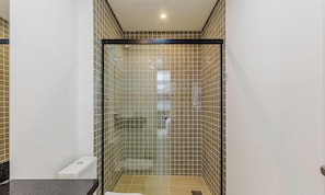 Une salle de bain moderne dotée d’une douche à parois de verre, de toilettes et d’un lavabo.
