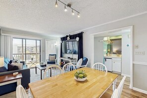 Een moderne woonkamer met een eettafel, een bank, een televisie en een keuken.