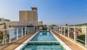 A rooftop pool with a clear view of the cityscape in the background. - VEC Lindos Studios (Bombinhas)