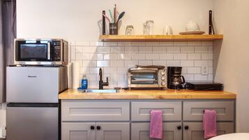 Une cuisine compacte équipée d’un four à micro-ondes, d’un grille-pain, d’une machine à café et d’un évier.