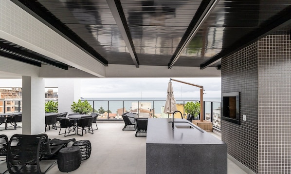 A rooftop terrace with outdoor seating, a TV screen, and a view of the sea. - VFR Estudios proximos a praia de Bombas (Bombinhas)