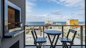 A balcony with a view of the sea, a table, and two chairs. - VFR Estudios proximos a praia de Bombas (Bombinhas)