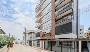 A multi-story building with a modern architectural design, featuring a mix of brick and glass facades. - VFR Estudios proximos a praia de Bombas (Bombinhas)