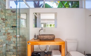A bathroom with a stone sink, a wooden vanity, a glass shower enclosure, and a toilet. - VGZ Cabanas Barra de Ibiraquera e Rosa (Imbituba)