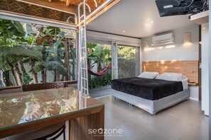Un dormitorio moderno con una cama, mesita de noche y un ventanal grande con vistas a un jardín.