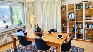 A dining area with a wooden table, black chairs, and a hanging light fixture. - 2 bedrooms in the heart of city center (Luxembourg City)