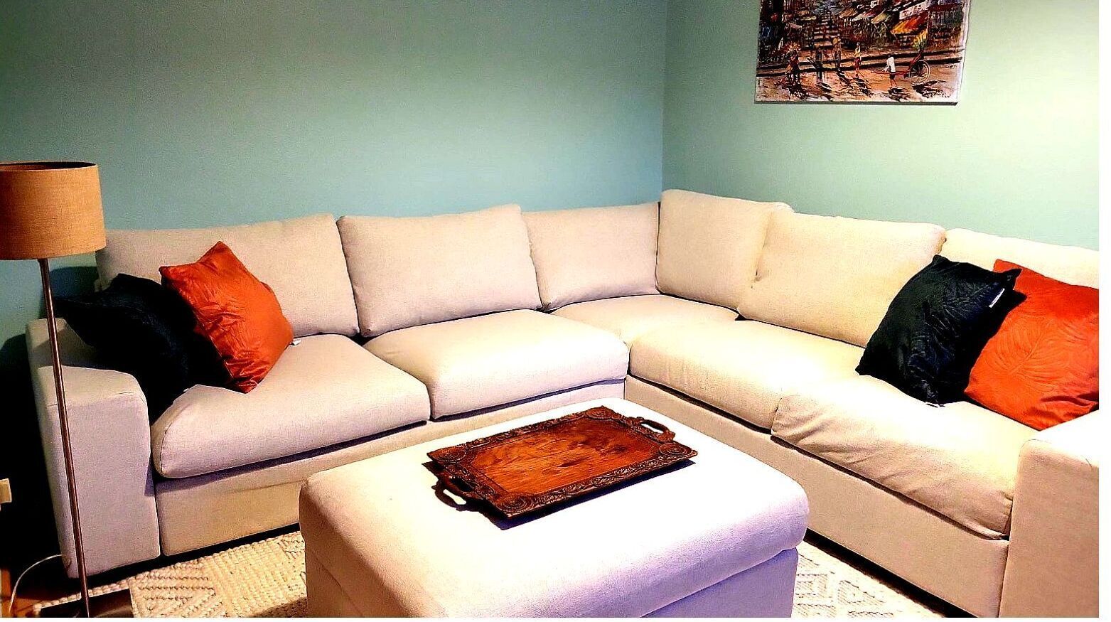 A living room with a beige sectional sofa, a wooden coffee table, and a lamp.