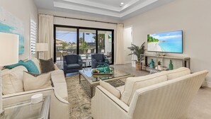 A spacious living room with a large television, comfortable seating, and a view of the outdoors. - Villa Del Mare Beach 4 Ensuite Retreat + Heated Pool – Special Offer! (Naples)