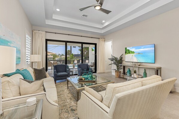 A spacious living room with a large television, comfortable seating, and a view of the outdoors.
