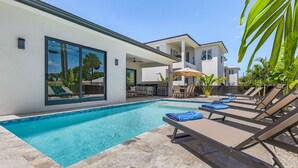 A modern house with a swimming pool, outdoor seating, and a covered patio area. - Villa Del Mare Beach 4 Ensuite Retreat + Heated Pool – Special Offer! (Naples)