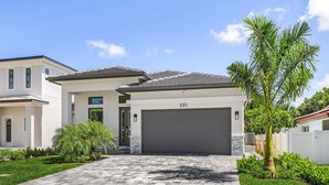 A modern two-story house with a grey garage door, number 531, and a well-maintained front yard with a palm tree and shrubs. - Villa Del Mare Beach 4 Ensuite Retreat + Heated Pool – Special Offer! (Naples)