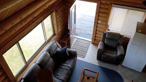 A cozy cabin interior with a sofa, armchair, and a small table.